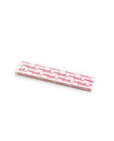 A close-up of Hollywood Fashion Secrets Hem Tape strips with branded red text, designed for easy temporary hemming.